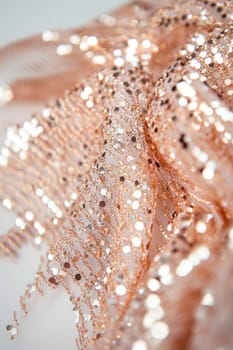 Close up of shimmering rose gold sequin fabric, showcasing texture and sparkle, perfect for fashion, crafts, or design projects