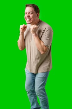 Man celebrating with a confident smile and raised fist against a bright green background in studio