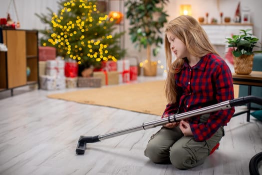 A person vacuums a festive room with a decorated Christmas tree, creating a cozy holiday atmosphere