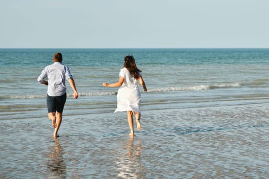 Back view of a couple running on the Atlantic ocean