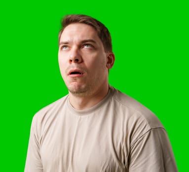 Man making a humorous expression against a bright green background in studio