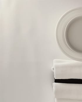 A simple, elegant arrangement of white ceramic plates and bowls set against a plain, off-white background, creating a serene and calming visual composition