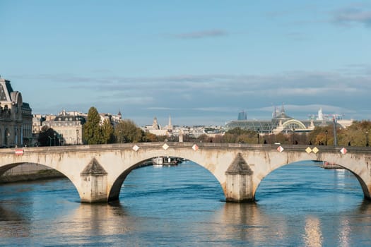 There is an impressive bridge spanning a tranquil body of water, with various buildings visible in the background, Paris, France - October 24, 2024