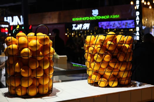 Colorful baskets of fresh oranges at a lively venue, showcasing produce in a stylish modern atmosphere