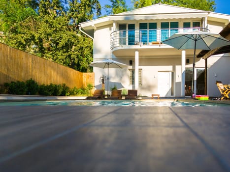 Modern residential house with swimming pool and patio. Luxury outdoor living space surrounded by greenery