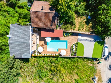 Aerial view of a modern backyard with a swimming pool, green lawn, and cozy patio