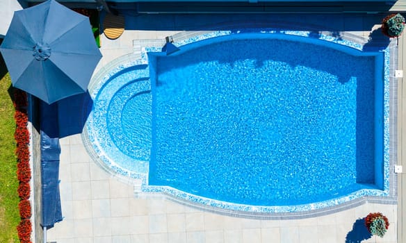 Top view of a luxurious oval pool with mosaic tiles and surrounding patio