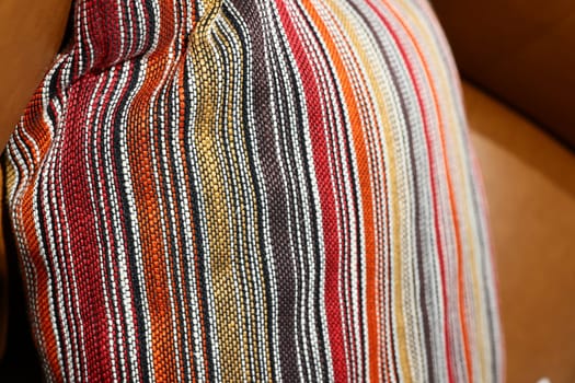 A striped decorative pillow enhances a leather sofas elegance, adding a cozy touch to the rooms ambiance