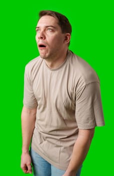 Man making a humorous expression against a bright green background in studio