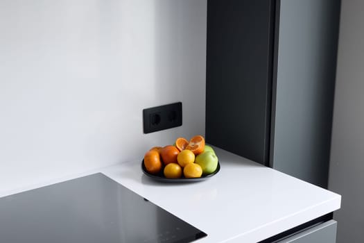 A contemporary kitchen showcases a vibrant bowl filled with a variety of fresh fruits on a clean white countertop
