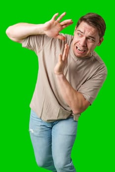 Man expressing fear while standing against a bright green background in studio