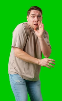 Man expressing fear while standing against a bright green background in studio