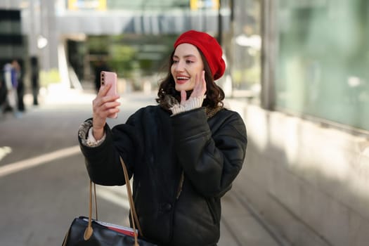A joyful woman wearing a bright red beret captures a vibrant selfie while thoroughly enjoying her day outdoors