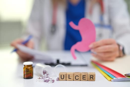 A knowledgeable doctor discusses stomach ulcers with a patient using informative visual aids and necessary medication