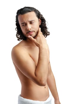 Young man with curly hair thoughtfully posing against a plain background in a studio setting