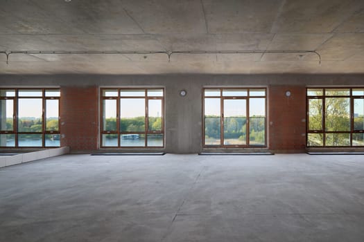 This spacious, empty room boasts large windows that let in an abundance of natural light, ideal for creative endeavors