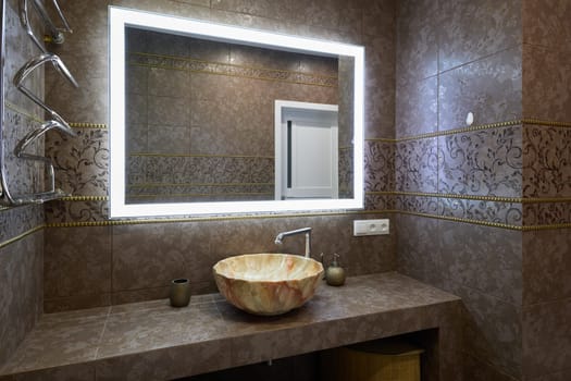 This bathroom is stylish, boasting a unique stone sink and a contemporary lighting design that enhances the vibe