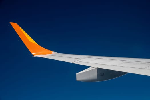 A plane wing extends against a deep blue sky. Travel concept.