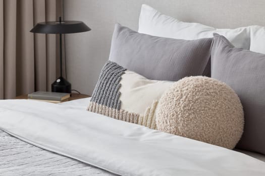 A serene modern bedroom featuring plush pillows, soft bedding, and a sleek lamp, perfect for relaxation.