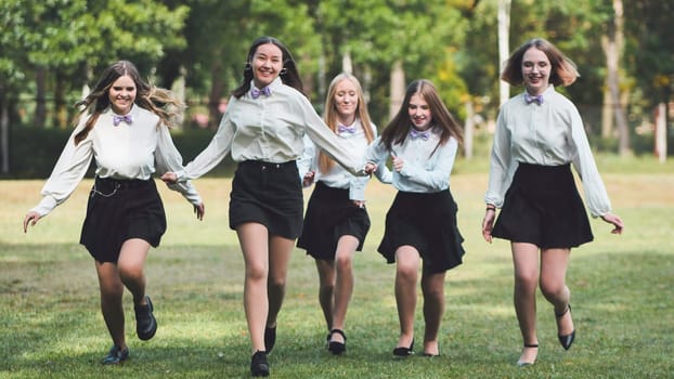 Five joyful schoolgirls joyfully running together in the park on their first day of school, relishing the moment and marking the beginning of a new school year with celebration