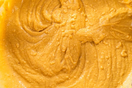 In a glass mixing bowl, a large hand whisk expertly blends the ingredients for a delectable gingerbread bundt cake with caramel frosting.
