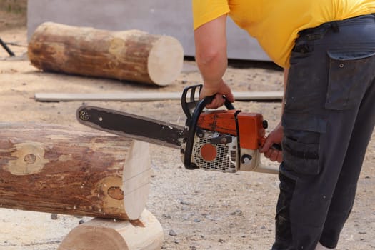 A highly skilled individual adeptly using a powerful chainsaw to cut timber logs for various woodworking projects