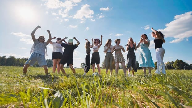 Group of cheerful high school students dancing and enjoying their summer break in a green field