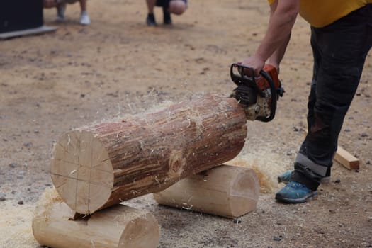 A participant uses a chainsaw to carve a log during a woodworking event, showcasing skill and precision.