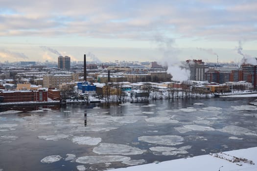 A picturesque snowy urban landscape showcasing factories, river ice formations, and serene winter scenery
