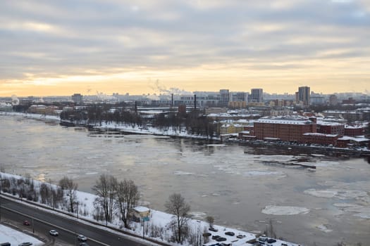 A tranquil winter scene beautifully showcasing a river encompassed by city buildings and stunning ice formations