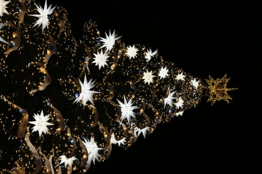 A stunning Christmas tree adorned with twinkling lights and shining stars in a dark, enchanting setting