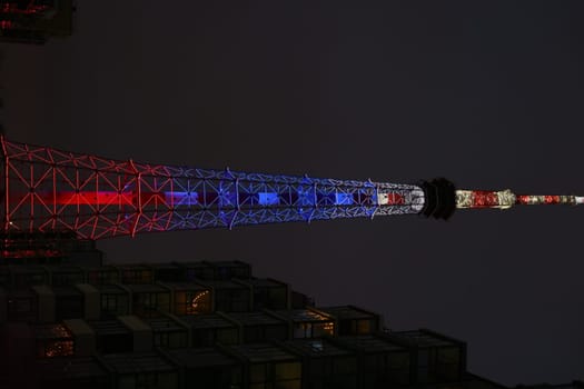 This stunning night view showcases a tower lit in red, white, and blue, capturing a festive atmosphere.