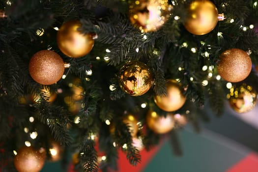 A closeup view of a beautifully decorated Christmas tree adorned with gold ornaments and sparkling twinkling lights