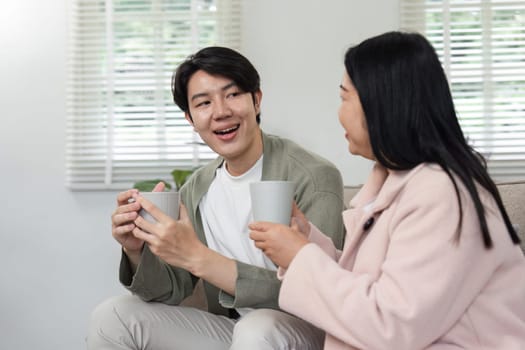 A mother and her son sit together at home, enjoying each other's company and engaging in relaxing activities during a holiday.