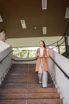 A confident businesswoman ascends stairs in a modern office, exuding professionalism and determination.