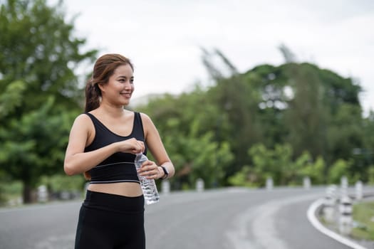 A woman in athletic wear exercising at the park, holding a water bottle, promoting hydration and outdoor fitness.