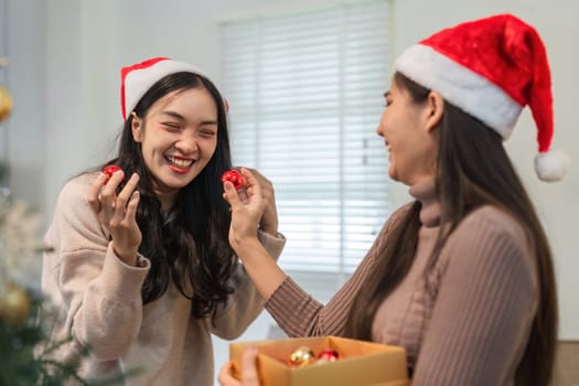 A young couple happily decorates their room for Christmas, adding festive ornaments and spreading holiday cheer together.