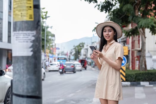 A young woman walks through the city, capturing the essence of modern urban life with her smartphone in hand.