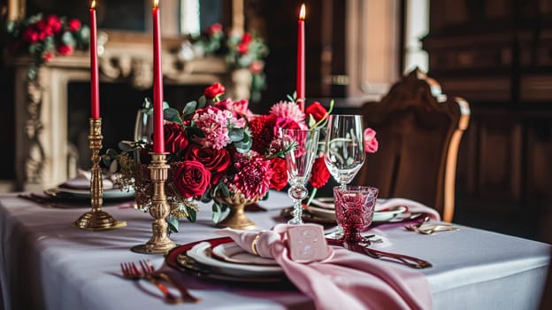 Festive table setting with candles and arrangement of beautiful red flowers. Holiday concept. High quality photo