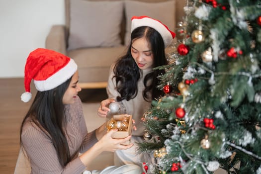 Happy young women celebrating Christmas with gifts and decorations by the tree, capturing festive joy and holiday spirit.