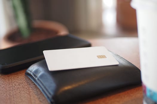 A simple and elegant wallet featuring a card, placed on a wooden table in a cozy atmosphere