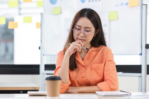 A young accountant in a modern office setting, focused on analyzing financial documents with a coffee cup and notepad nearby.