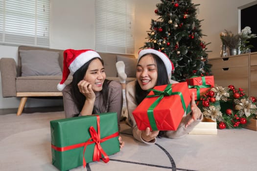 Joyful lesbian couple celebrating Christmas with gifts, laughter, and festive decorations in a cozy home environment.