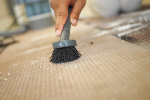 A hand diligently using a brush to remove dust from a surface, ensuring cleanliness and hygiene