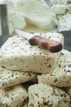 Several blocks of delicious herbal cheese artfully arranged with a wooden knife placed on top