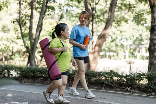 Two women jogging together in a park, embracing fitness and friendship in a natural setting.
