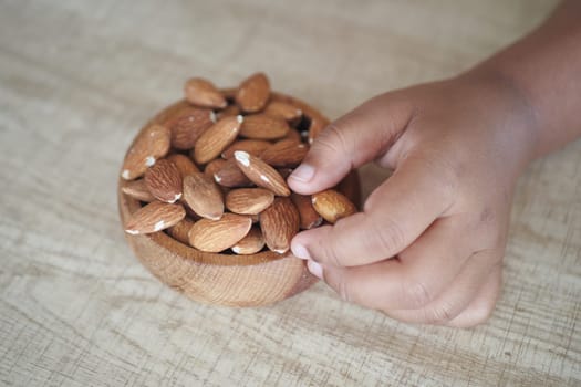 Close up of child hand pick almond nut .