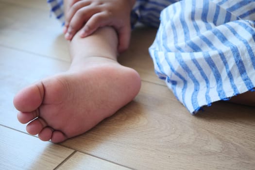 A closeup photograph captures a childs tiny foot resting comfortably on a wooden floor