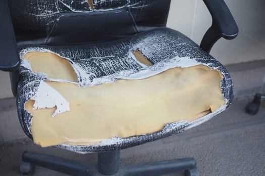 This damaged office chair shows wear and reveals its exposed interior materials