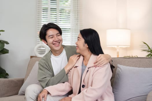 A mother and her son are sitting together on a couch, smiling and enjoying each other's company during a holiday at home.